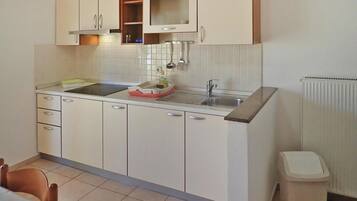A compact kitchen with white cabinets, a built-in oven, and a sink.