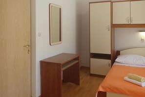 A bedroom with a bed, a wooden desk, a wardrobe, and a mirror. - House in Starigrad near Paklenica Park (Starigrad Paklenica)