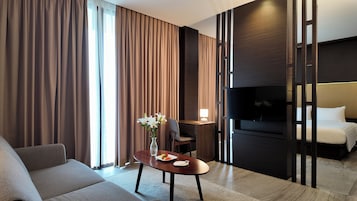 Una habitación de hotel con sofá, una mesa de comedor con un jarrón de flores, televisor y cama.