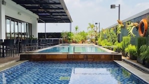 A pool area with two pools, outdoor seating, and a covered patio. - Laska Hotel Sukabumi (Sukabumi)