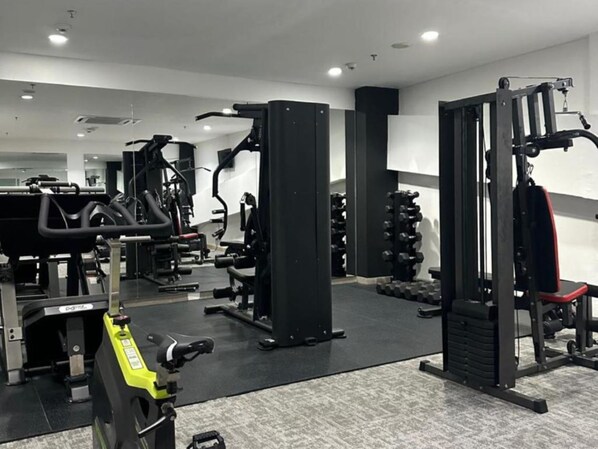 A gym with various exercise equipment, including a treadmill, weight machines, and free weights.