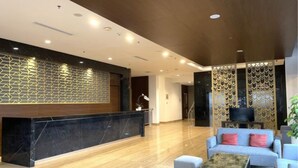 A modern lobby with a reception desk, seating area, and decorative panels. - Laska Hotel Sukabumi (Sukabumi)