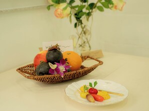 A fruit basket with a plate of assorted fruits and a small card.