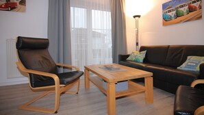 A living room with a black leather chair, a wooden coffee table, a black leather sofa, and a floor lamp. - Ferienwohnung auf Fehmarn in Orther Reede (Orth)