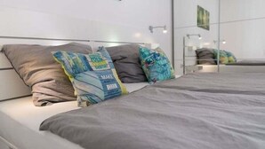A modern bedroom with a bed, grey bedding, and decorative pillows. - Ferienwohnung auf Fehmarn in Orther Reede (Orth)