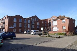 Useita kerroksia sisältävä tiilirakennus, jonka edessä on parkkipaikka.
