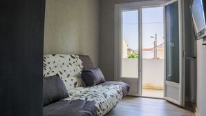 Een moderne woonkamer met een bank, een televisie en een schuifdeur naar een buitenruimte.