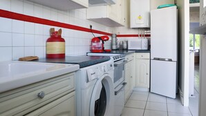 Een keuken met een wasmachine, magnetron en koelkast.