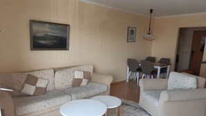 Un soggiorno con un divano, due tavolini, una zona pranzo con sedie e un quadro appeso al muro.