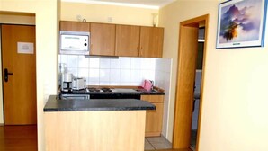 Una cucina compatta con mobili in legno, un piano di lavoro nero e un piano cottura integrato.