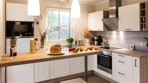 A modern kitchen with white cabinets, a wooden countertop, and pendant lighting. - Komfortables Ferienhaus mit Sauna in Fuhlendorf (Fuhlendorf)