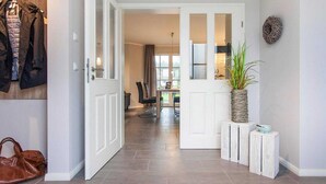A hallway with a coat rack, a door, and a plant on a side table. - Komfortables Ferienhaus mit Sauna in Fuhlendorf (Fuhlendorf)