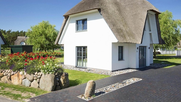 A modern house with a thatched roof, white exterior walls, and a paved driveway. - Komfortables Ferienhaus mit Sauna in Fuhlendorf (Fuhlendorf)
