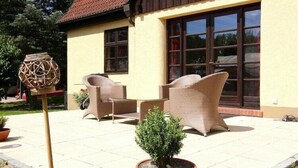 Une terrasse avec des meubles en osier et une plante en pot.