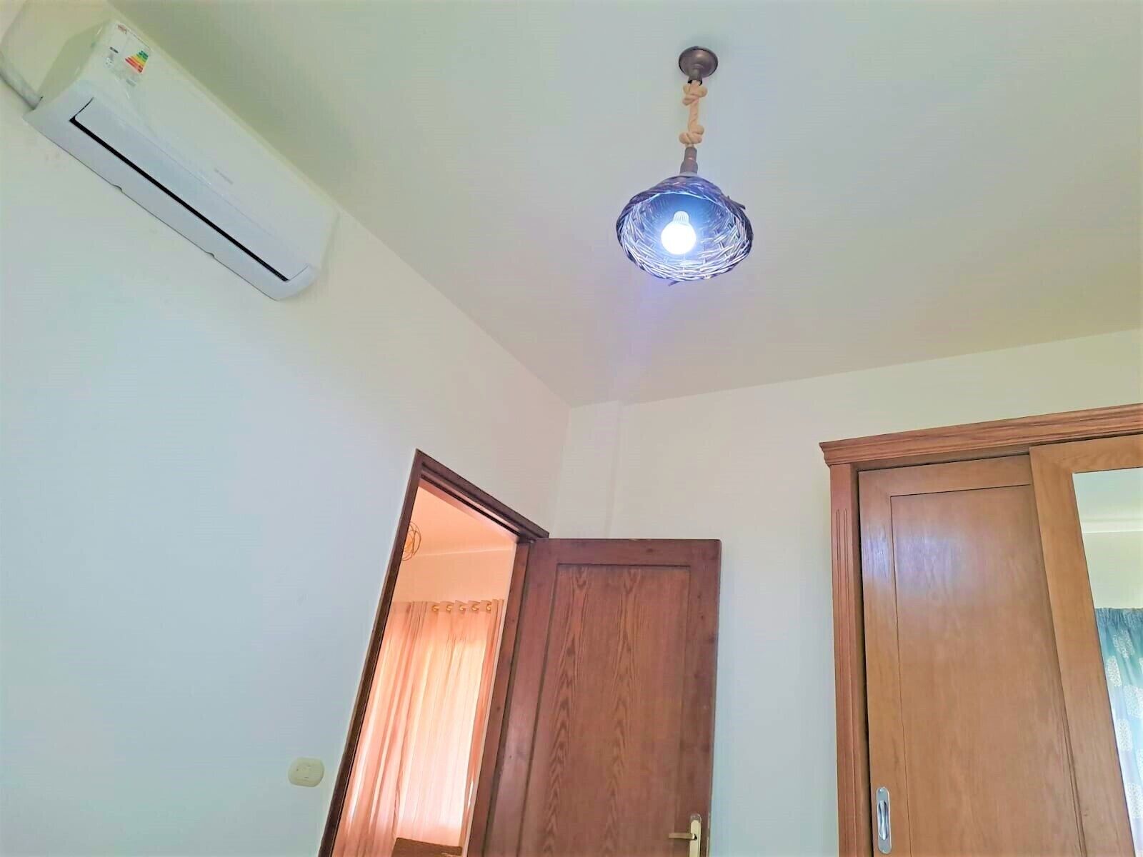 Une pièce dotée d’un ventilateur de plafond, d’un climatiseur et d’une porte en bois.