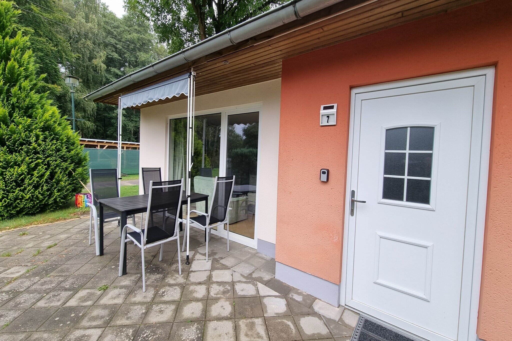 A patio with a table and chairs, a door, and a small window.