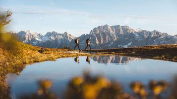 Dos personas caminando por un sendero, con un paisaje montañoso al fondo.