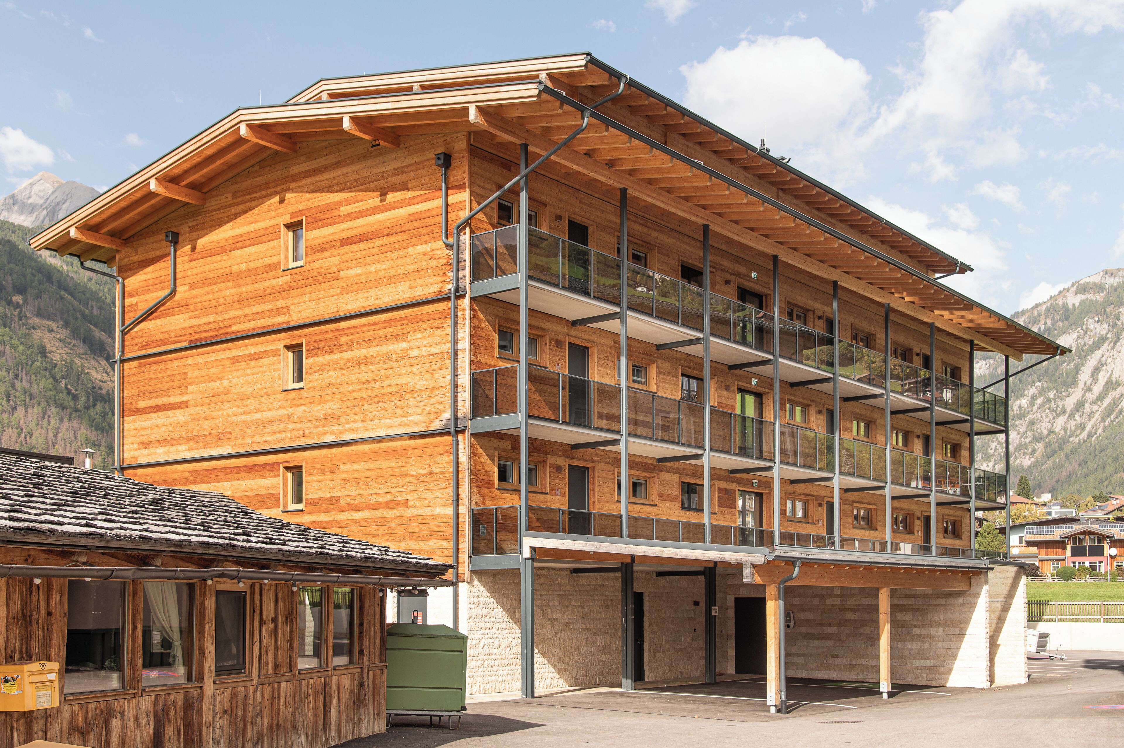 A multi-story wooden building with balconies and a covered entrance area.
