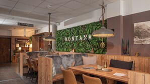 Un restaurant avec des banquettes en bois et un mur sur lequel est écrit le mot « MONTANA ». On y trouve des tables et des chaises, ainsi qu’un panneau indiquant « NationalParkInfo ».