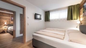 Ein modernes Schlafzimmer mit Bett, Fernseher und einem Fenster mit Vorhängen.