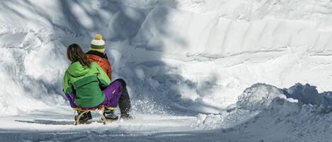 Two people sledding down a snowy slope.