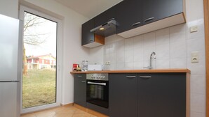 A modern kitchen with a built-in oven, a coffee maker, and a window overlooking a residential area. - Reihenhaus am Groß Labenzer See, Klein Labenz (Klein Labenz)
