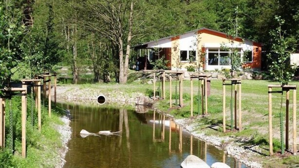 A rustic cabin with a pond, surrounded by trees and wooden structures. - Reihenhaus am Groß Labenzer See, Klein Labenz (Klein Labenz)