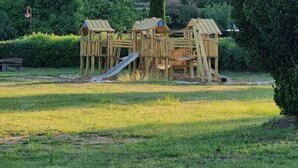 A wooden play structure with multiple slides and climbing areas in a grassy park area. - Reihenhaus am Groß Labenzer See, Klein Labenz (Klein Labenz)