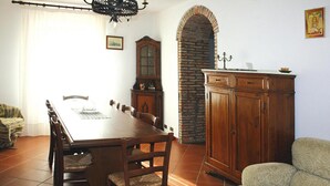 A dining room with a wooden table, chairs, a cabinet, and a patterned armchair.