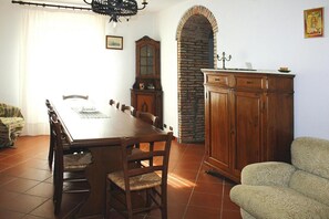 Un comedor con una mesa de madera, sillas, un aparador y un sillón estampado.