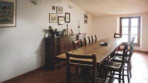 A dining room with a long wooden table, chairs, a cabinet with decorative items, and framed pictures on the wall.