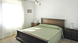 A bedroom with a wooden bed, a nightstand, a bedside table, and a hanging light fixture.