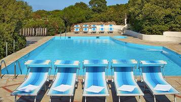 A swimming pool with blue and white lounge chairs arranged in rows.