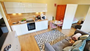 Un espace de vie compact comprenant un coin cuisine, un coin repas et un coin salon avec un canapé et un tapis à motifs.