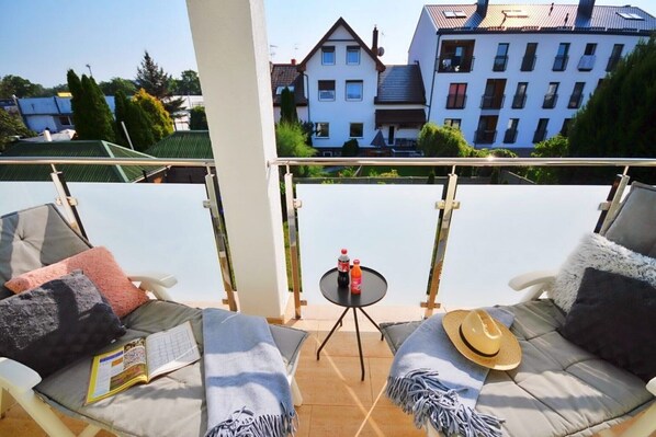 A balcony with two chairs, a small table with drinks, and a book.