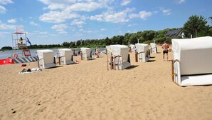 Beach chairs lined up on the sand, a lifeguard tower, and a row of beach huts.
