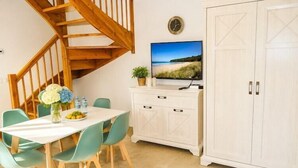 A dining area with a table, chairs, a TV, and a staircase.