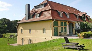 A two-story house with a sloped roof, a chimney, and a green door. - Ferienhaus Birgit, Wendorf (Wendorf)