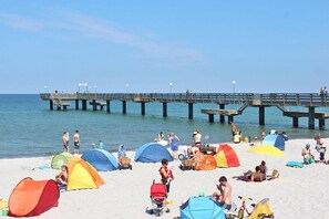 A beach with colorful tents and a pier extending into the water. - Ferienhaus, Boiensdorf (Boiensdorf)