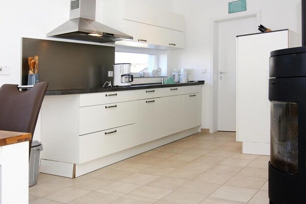 A modern kitchen with white cabinetry, a stainless steel range hood, and a black refrigerator.