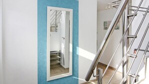 Un intérieur moderne avec un mur d’accent bleu, une porte miroir et un escalier en métal.