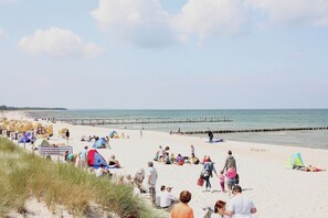 A beach with people, tents, and a pier.