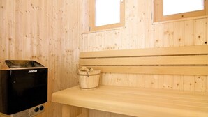 Una sala de sauna con un banco, un calentador de sauna Harvia y un cubo de madera.