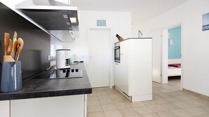 Een moderne keuken met witte kasten, een zwart aanrecht en een koffieapparaat.