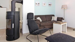 Een moderne woonkamer met een bank, een fauteuil, een bijzettafeltje en een open haard.
