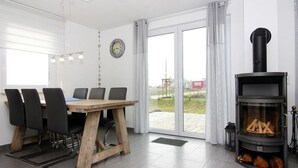 Un salon moderne comprenant une table à manger, des chaises, une cheminée et une grande fenêtre avec des rideaux.