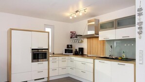 Une cuisine moderne avec des armoires blanches, des appareils en acier inoxydable et un plan de travail en bois.