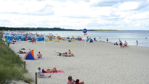 Une plage où l’on voit de nombreuses tentes et des gens qui se détendent.