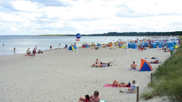 Une plage avec des tentes et des gens qui prennent un bain de soleil.