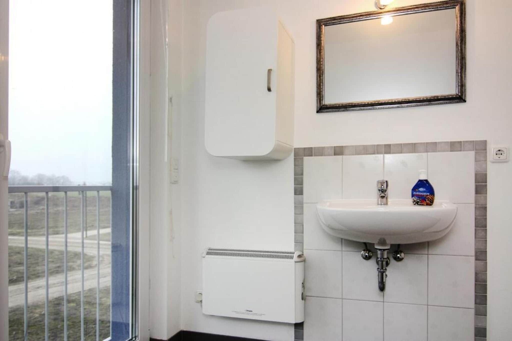 A bathroom with a white sink, a mirror, a cabinet, and a heater.
